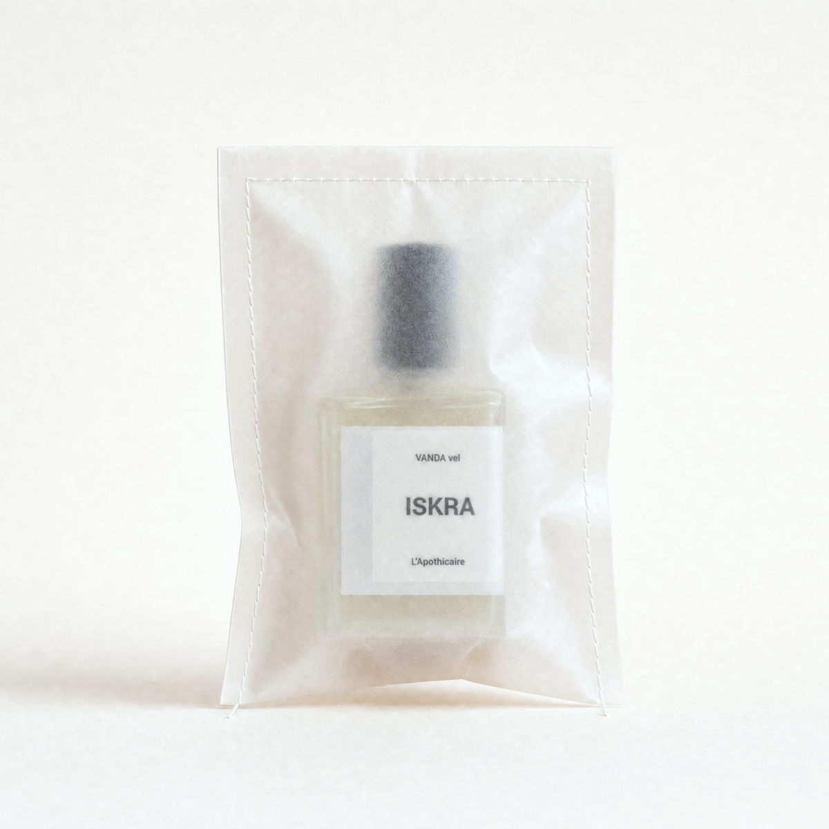 A small clear plastic pouch containing a rectangular glass bottle with a white label reading 'ISKRA' and 'VANDIA vol.' on a warm off-white background.