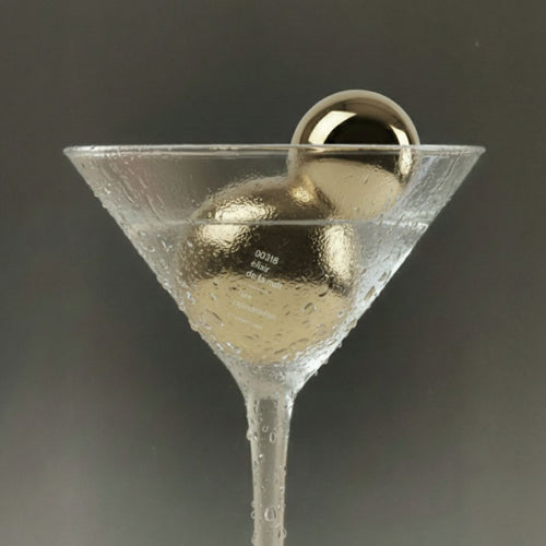 Martini glass with a gold perfume bottle e on a dark background